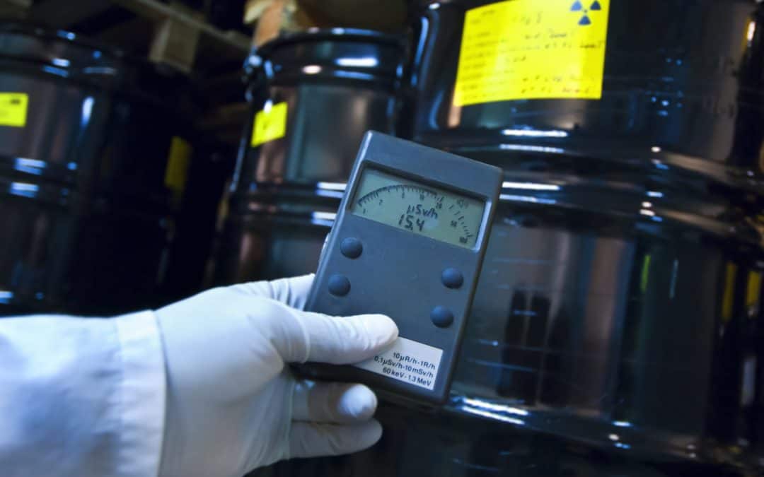 Dose rate being shown on a meter in front of a container with a radioactive trefoil labe.